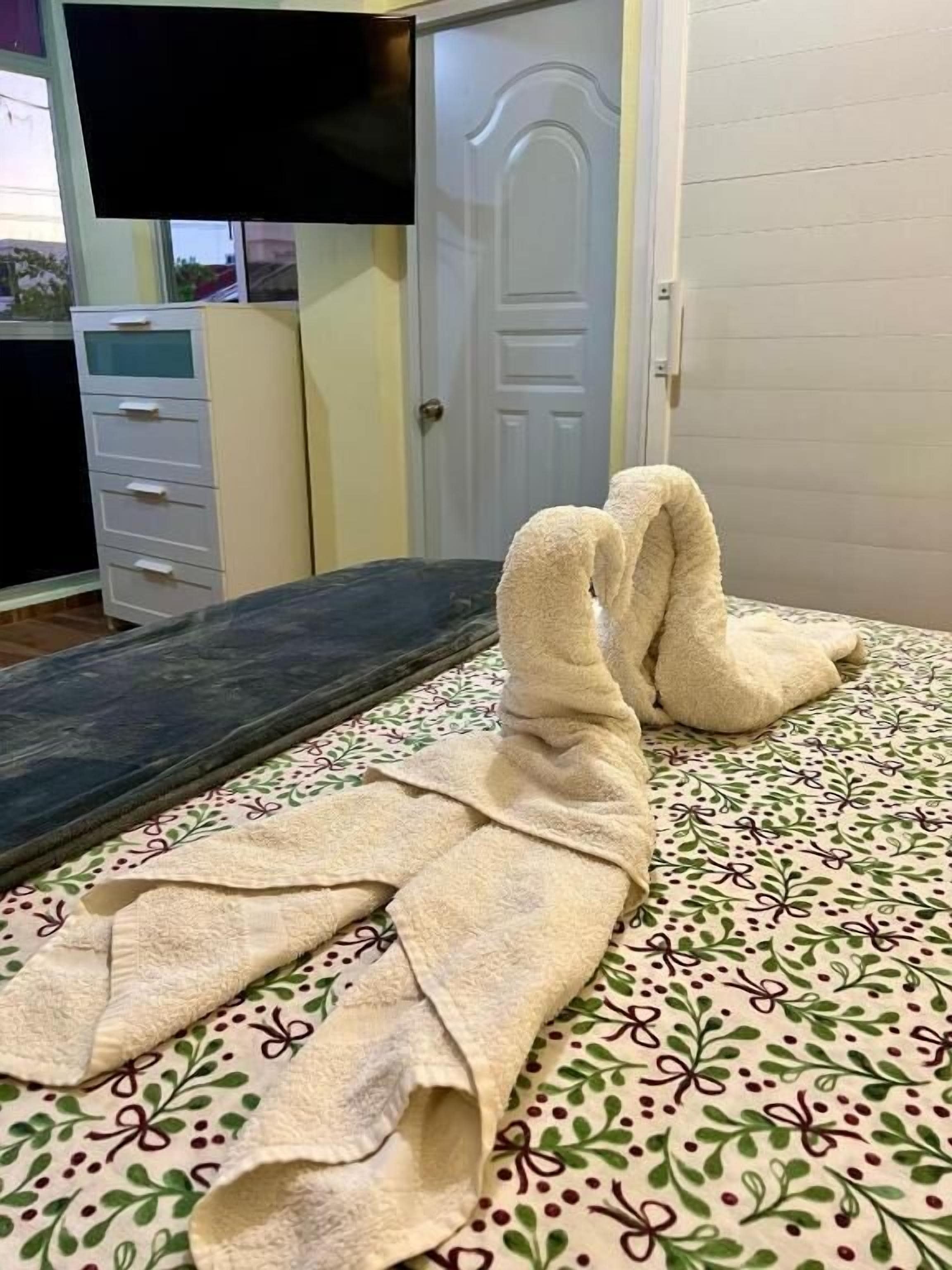 Una cama con un edredón estampado y una toalla doblada en forma de conejo.
