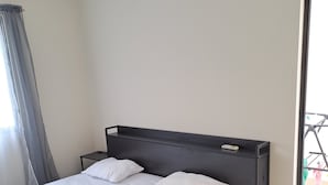 A single bed with a headboard, two pillows, and a bedside table in a room with a window and a door. - 2 double rooms in Cancun (Cancún)