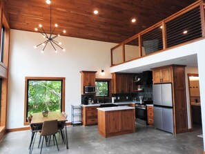 Una cocina moderna con armarios de madera, una isla central y un comedor con sillas.
