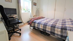 A bedroom with a bed, a desk with a computer, a chair, a wardrobe, and a window with curtains. - A good flat close to university! (Manchester)