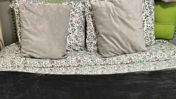 Una cama con colchón negro y ropa de cama estampada con motivos florales.
