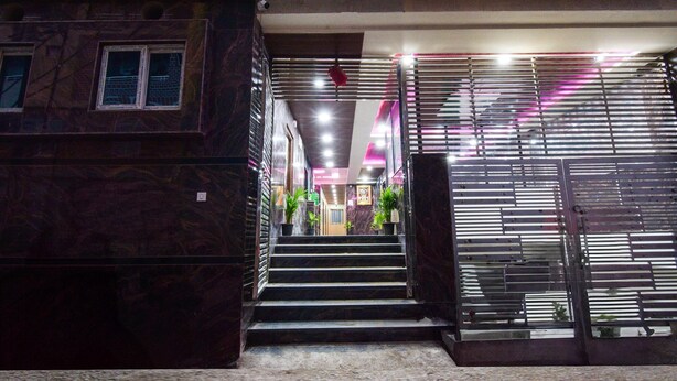A building entrance with a staircase leading to a second floor, metal railings, and potted plants. - Deluxe Aarian Tej Nilayam (Hyderabad)