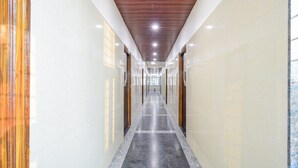 A long, narrow hallway with a polished floor, wooden ceiling panels, and glass doors on both sides. - Deluxe Aarian Tej Nilayam (Hyderabad)