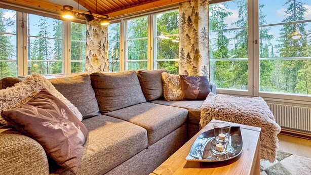 Una habitación acogedora con techo de madera, ventanas amplias, un sofá y una mesita auxiliar con una bandeja.