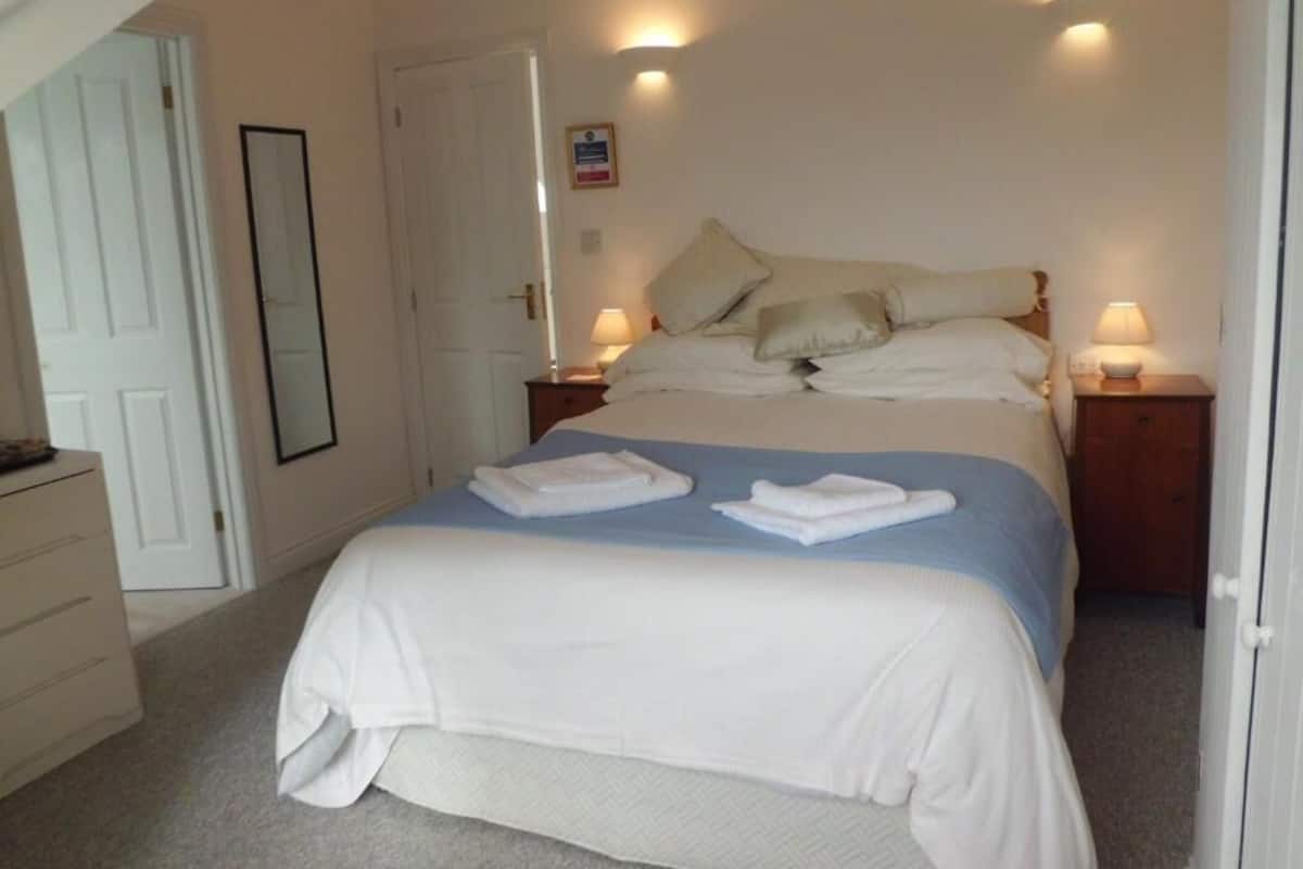 A bedroom with a bed, two bedside tables, a dresser, and a door.