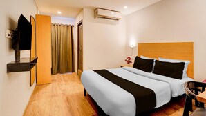 A hotel room with a bed, a TV mounted on the wall, an air conditioning unit, and a wooden headboard. - Deluxetownhouse Sarjapur Near Bellandur (Bengaluru)