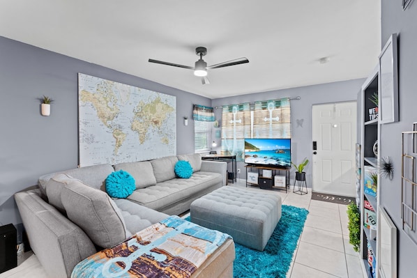 A modern living room with a sofa, ottoman, and a world map on the wall.