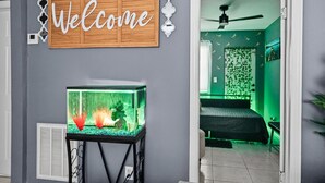 Een kamer met een aquarium, een welkomstbord, een bed en een plafondventilator.