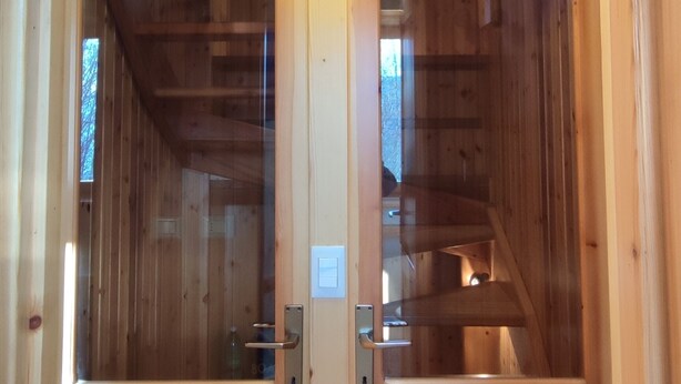A wooden door with a glass panel, a light fixture above, and a visible electrical outlet. - Baita Carlito - Quiet and sunny setting overlooking the forest (Sueglio)