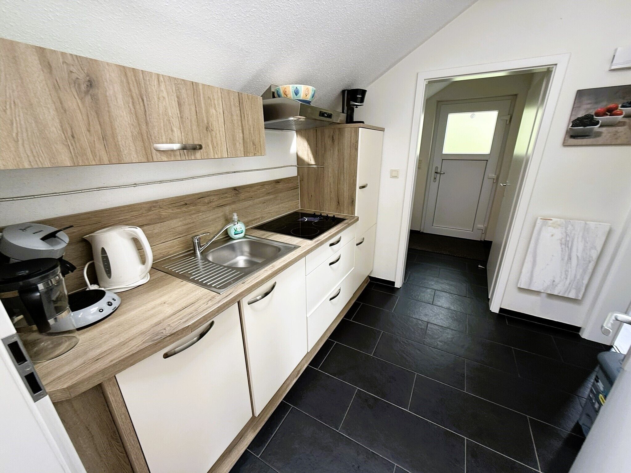 A modern kitchen with a wooden countertop, stainless steel sink, and white cabinets.