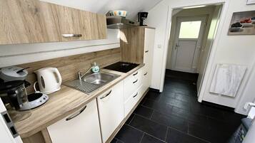 A modern kitchen with a wooden countertop, stainless steel sink, and white cabinets.