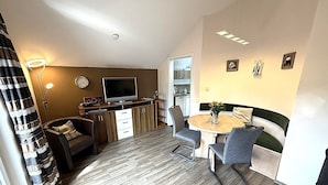 A compact living space with a dining table, sofa, TV, and kitchenette. - Peaceful COZY Apartment in Bavarian Forest +WIFI (Grafenwiesen)
