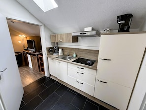 A compact kitchen with a stove, sink, cabinets, and a coffee maker. - Peaceful COZY Apartment in Bavarian Forest +WIFI (Grafenwiesen)