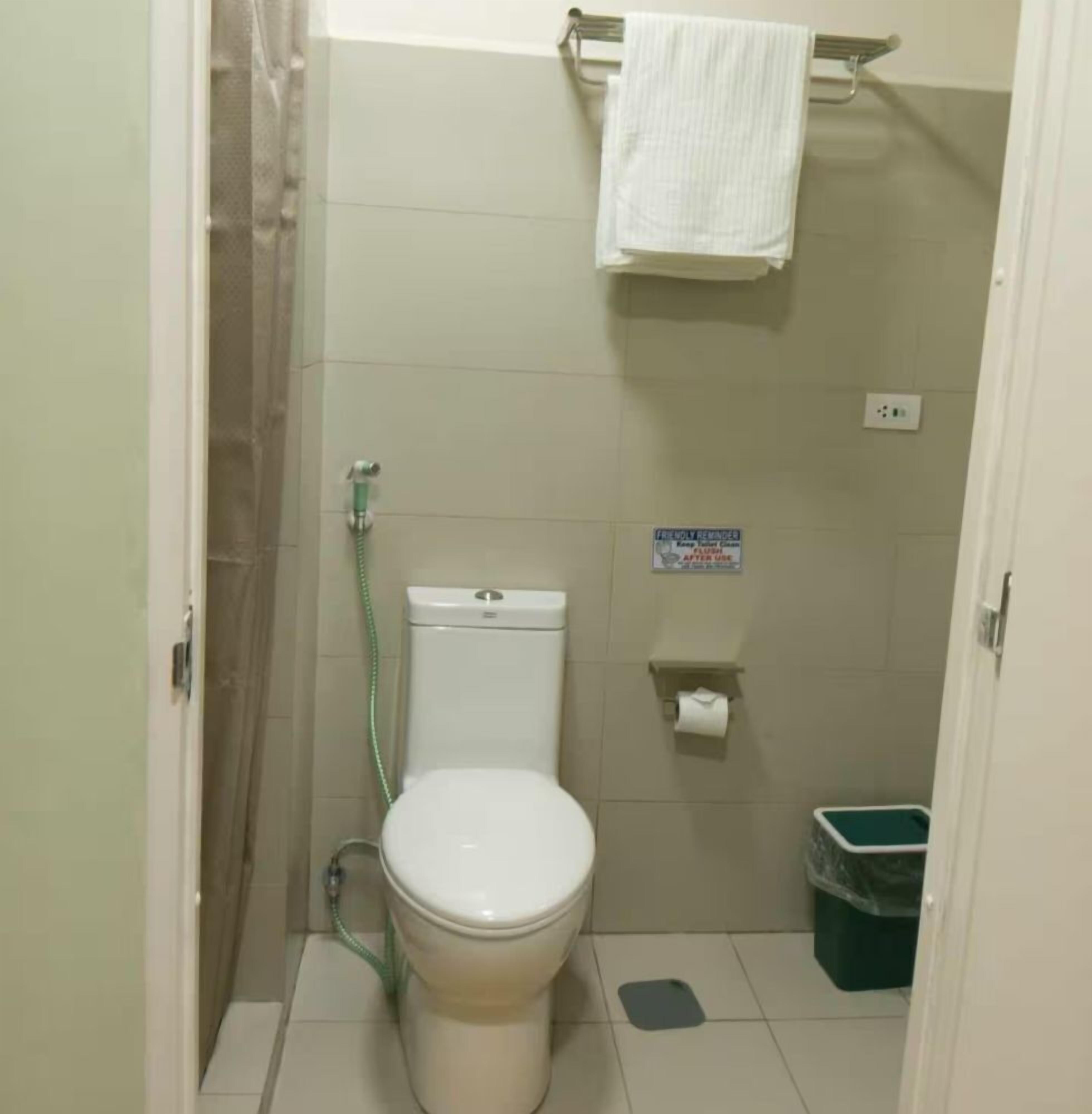 A small, clean bathroom with a toilet, a shower, and a trash bin.