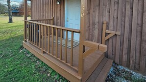Eine Holzhütte mit Veranda, einer Tür mit einer Hausnummer und einem Briefkasten.
