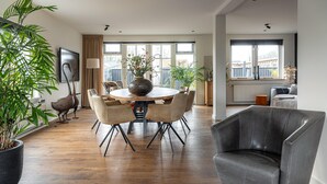 Ein modernes Wohnzimmer mit einem runden Esstisch, Ledersesseln, einer großen Topfpflanze und einem schwarzen Ledersessel.