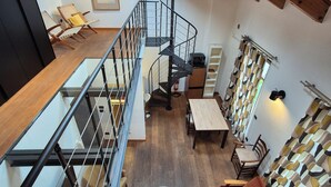 A spacious loft with a mezzanine, a staircase, a round coffee table, and a sofa. - Urban Loft Duomo - One Bedroom Apartment, Sleeps 2 (Alba)