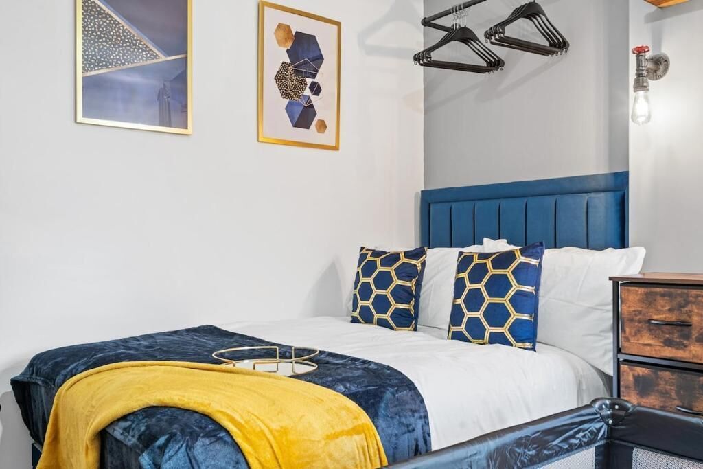 A bed with a blue headboard, white bedding, and decorative pillows with a geometric pattern.