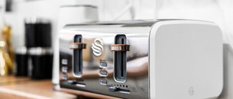 Une cuisine moderne dotée d’appareils électroménagers en acier inoxydable, d’un plan de travail en bois et d’un revêtement mural blanc.
