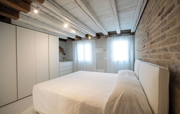 Una camera da letto con un letto, un armadio, uno specchio e una parete in mattoni.