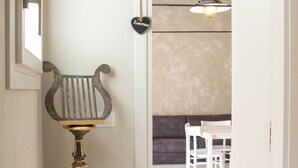 A hallway with a decorative metal stand, a door leading to a room with a sofa and a table, and a hanging light fixture. - Dimora Limonio -Damare- Pellestrina Ve (Venezia)