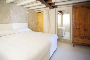 Una camera da letto con un letto grande, un armadio in legno e uno specchio che riflette un letto nella stanza accanto.