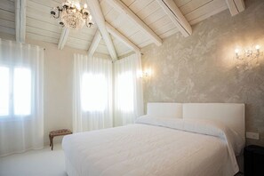 A bedroom with a large bed, wooden beams, a chandelier, and a textured wall. - Dimora Leccio -Damare- Pellestrina Ve (Venezia)