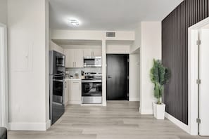 A modern kitchen with stainless steel appliances, a central island, and a dark wooden accent wall.
