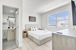 Une chambre d’hôtel moderne avec un grand lit, une table de chevet, un miroir et une fenêtre donnant sur un beau paysage.