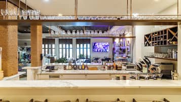 A bar area with a counter, bar stools, and a variety of bottles and glasses.