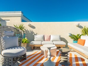 Un espace extérieur moderne aménagé avec un canapé, des fauteuils et une table ronde.