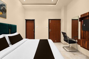 A hotel room with a bed, two doors, a chair, a TV, and a painting on the wall. - Deluxekhandaka Villa (Amer)