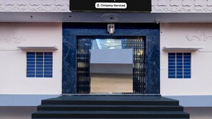 Ein Gebäudeeingang mit Schild, das unternehmensseitlichen Service kennzeichnet, eine Treppe, die zum Eingang führt, und einer Zierteindeckung.