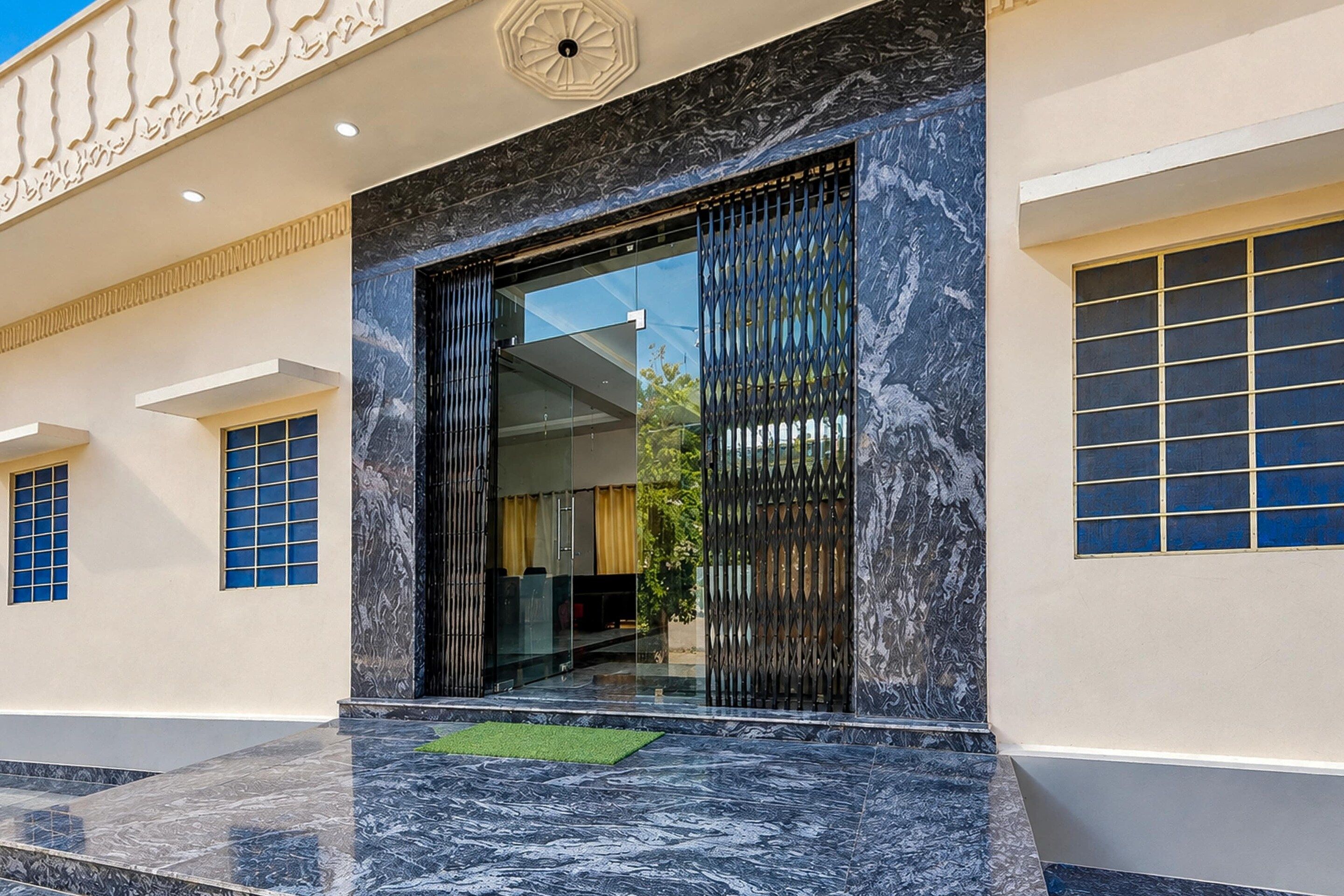 A modern building entrance with a glass door, a marble floor, and a decorative ceiling.