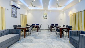 Ein Konferenzraum mit Marmorboden, zwei Sofas, einem Tisch mit Stühlen, Deckenventilatoren und Wandklimaanlage.