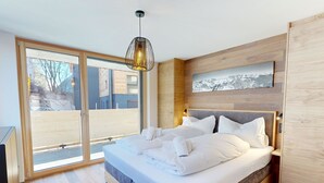 Ein modernes Schlafzimmer mit einem großen Bett, Holzboden, einer Schiebeglastür zum Balkon und einem Wandbild.