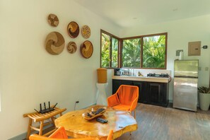 A compact kitchen with a window, a dining area with a table and chairs, and a refrigerator.
