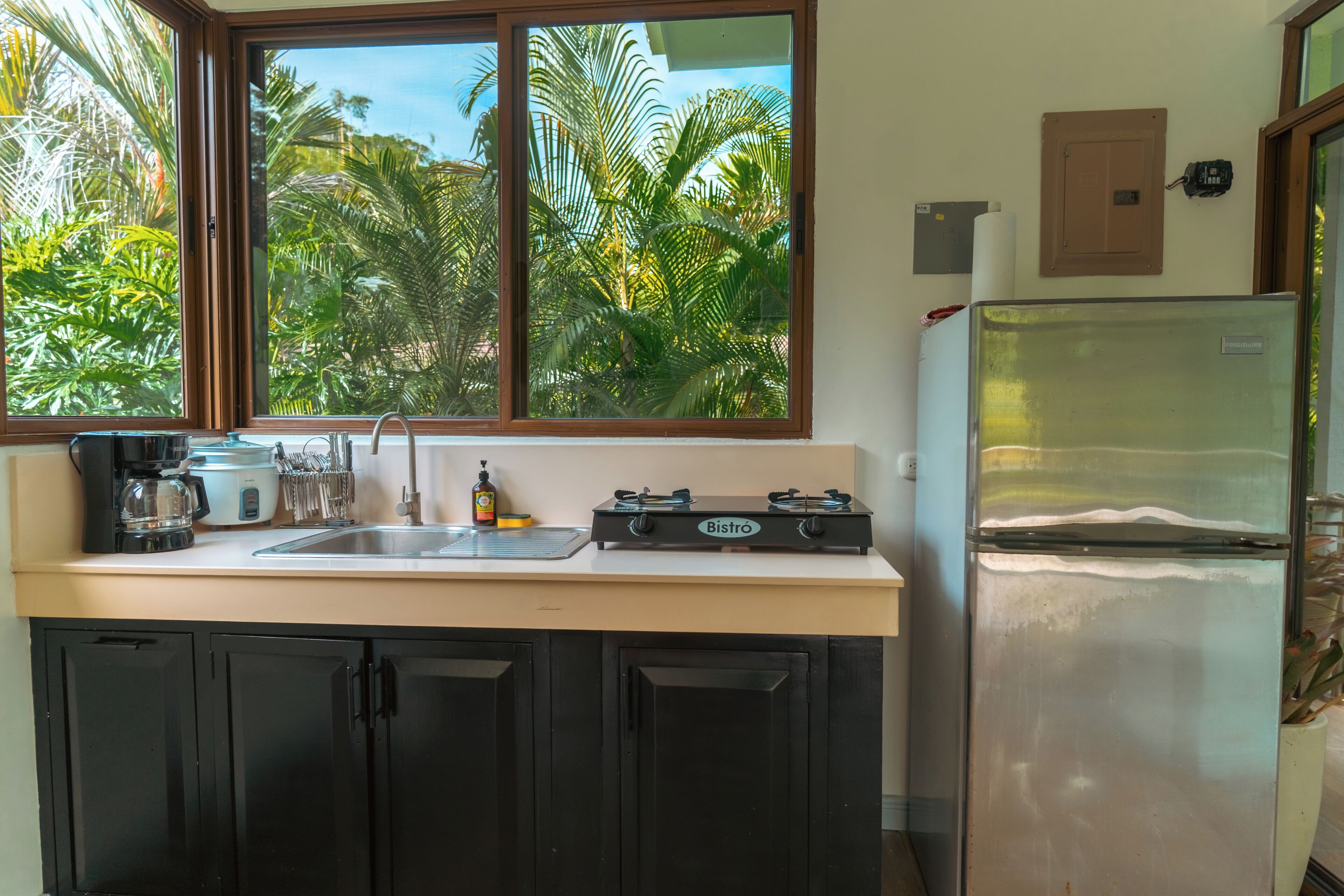 A kitchen with a window, a sink, a stove, and a refrigerator.