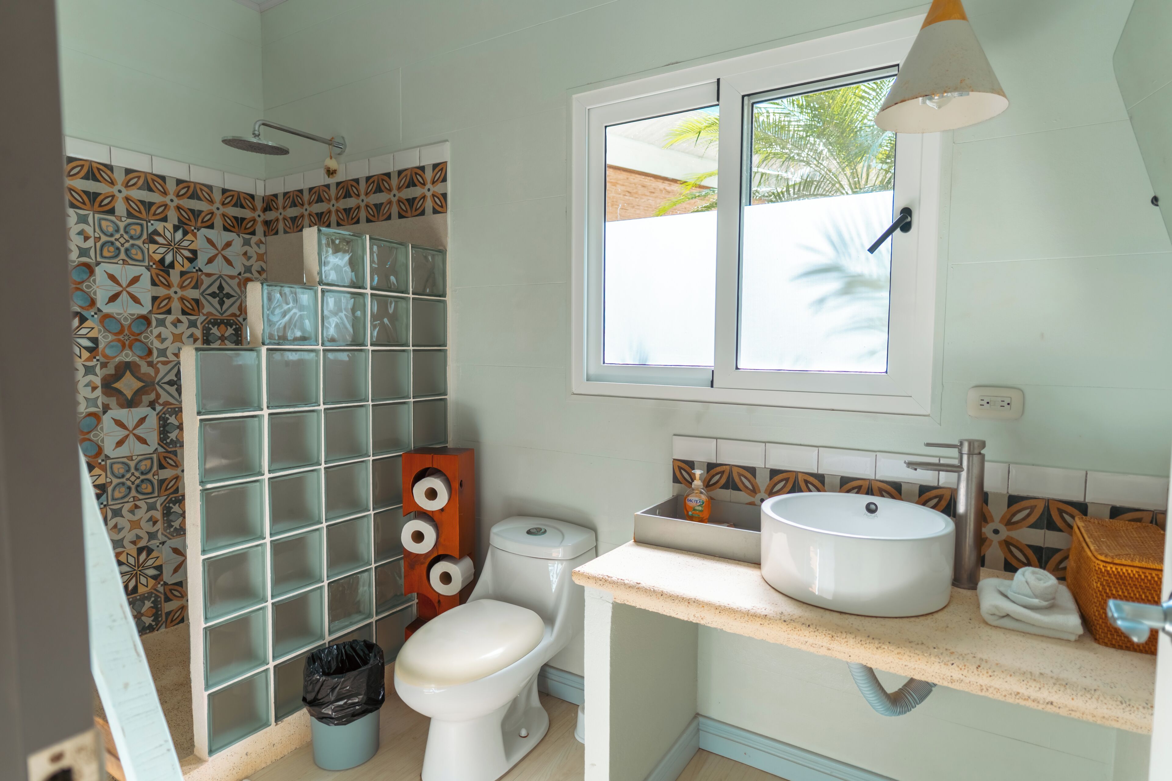 A bathroom with a toilet, sink, shower, and decorative tiles.