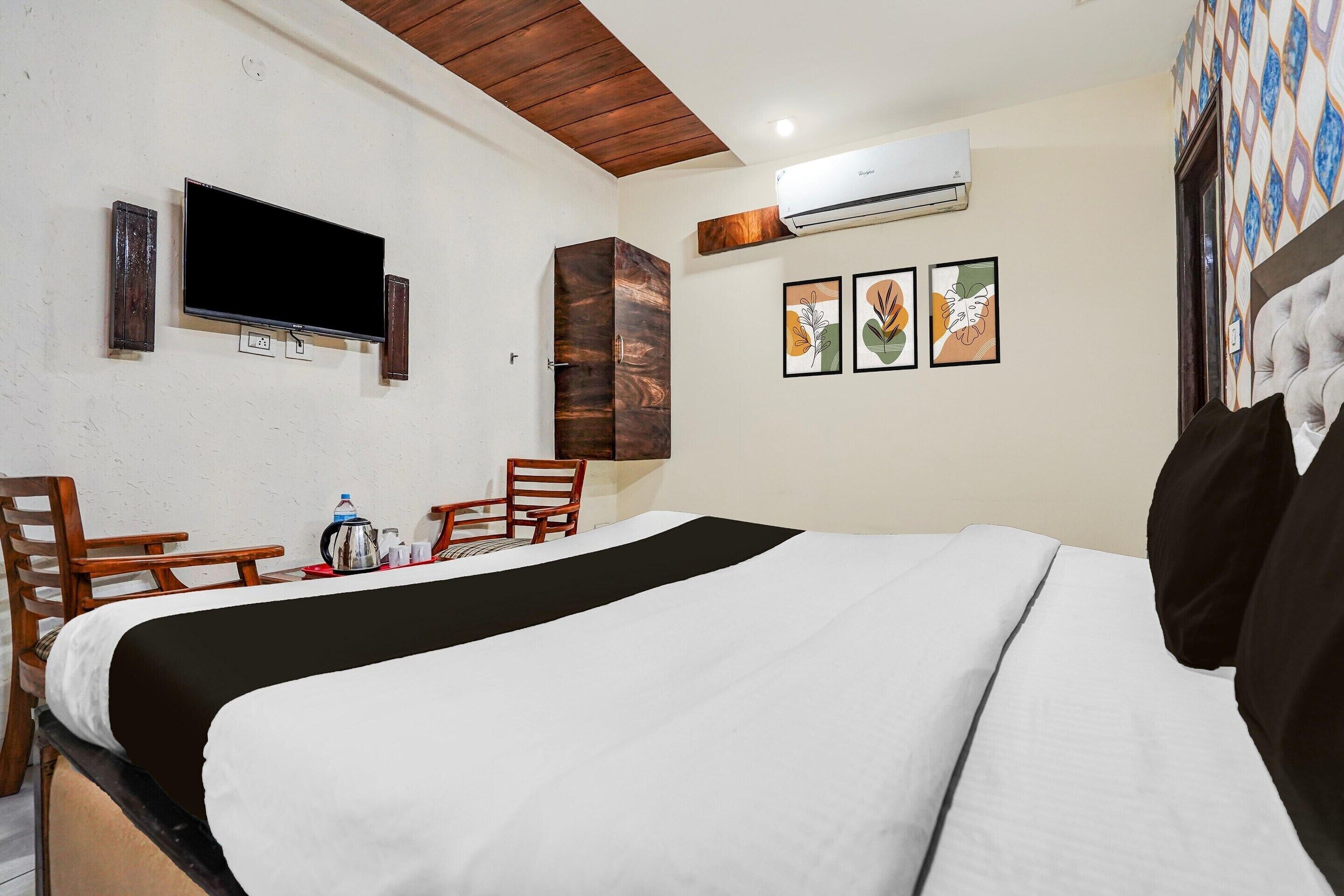 A hotel room with a bed, a TV, a coffee maker, and a chair.