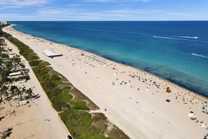 A beach with a long stretch of sand, a few umbrellas, and a few people. - Cozy South Beach 1BR Near Beach & Nightlife 310 (Miami Beach)