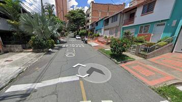 Una calle residencial con casas, una escuela y cielo despejado.