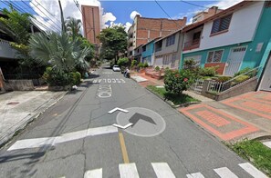 Una calle residencial con casas, una escuela y cielo despejado.