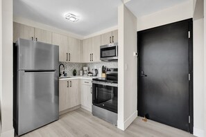 Una cocina moderna con electrodomésticos de acero inoxidable, armarios de madera y una puerta negra.