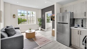 Una cocina moderna con un refrigerador de acero inoxidable, armarios de madera y un ventanal con vistas a la vegetación.