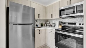 Una cocina moderna con electrodomésticos de acero inoxidable, armarios de madera y un salpicadero de azulejos tipo espiga.
