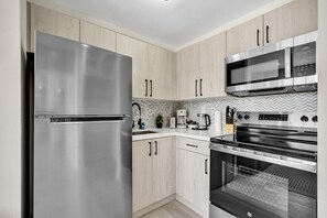 Eine moderne Küche mit Edelstahlgeräten, Holzschränken und einer Fischgrätmuster-Fliesenrückwand.