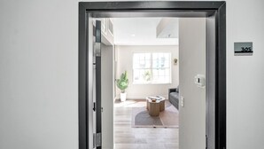 Un interior moderno con una puerta que indica '305', un ventanal grande, una planta en maceta y una mesa redonda.