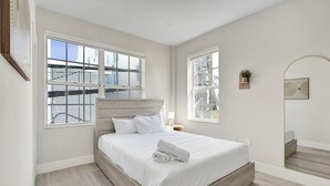 Una camera da letto con un letto grande, due finestre, un comodino e uno specchio.
