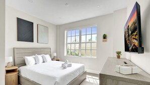 Una habitación de hotel moderna con una cama grande, un escritorio, un televisor y una ventana con vistas.